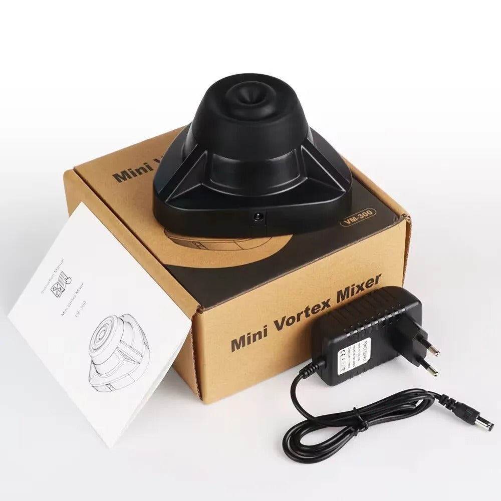 Image of a Mini Vortex Mixer kit featuring a black mixer placed on its packaging box. The kit includes an instruction manual and a power adapter. The design is compact and suitable for laboratory or small-scale mixing applications
