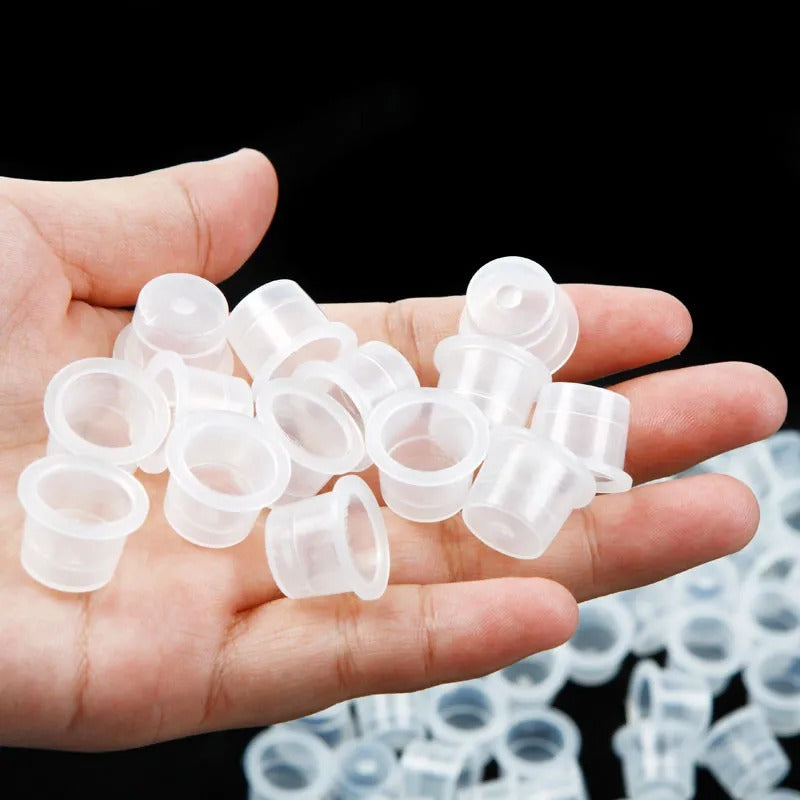 A close-up image of a hand holding several transparent conical paint caps, showcasing their lightweight and practical design for professional use.