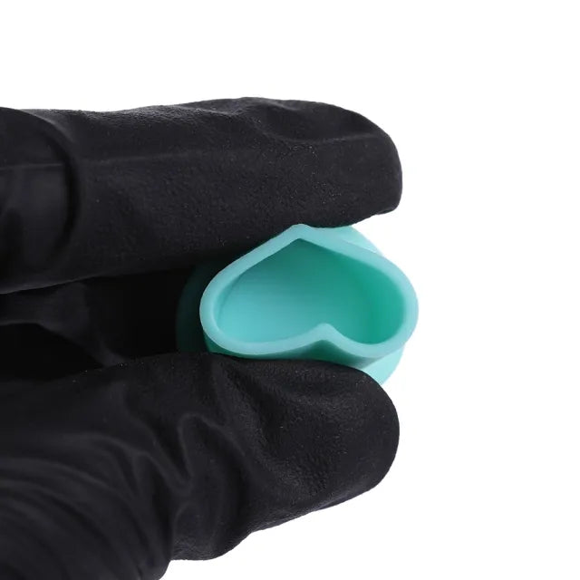 Tattoo artist holding a silicone ink cup, showcasing its softness and flexibility.