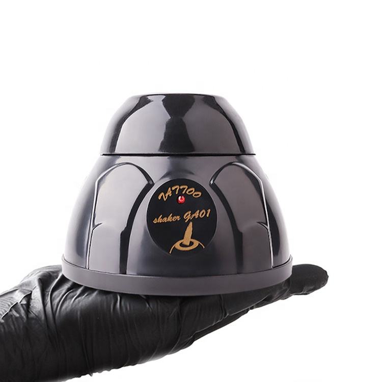 Compact tattoo ink mixer held in a gloved hand, highlighting its portable design.