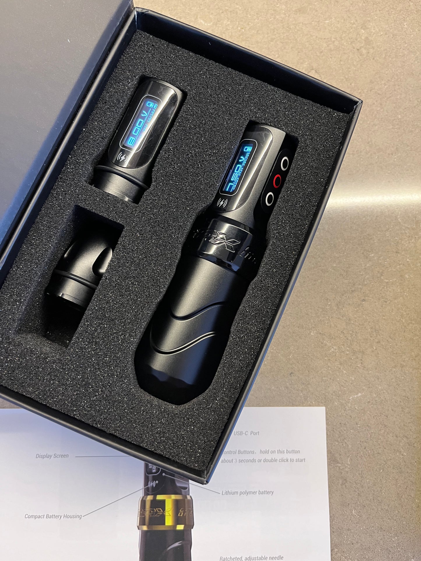 Photograph of a black wireless 'Pen' type machine with its box opened to reveal two batteries inside.