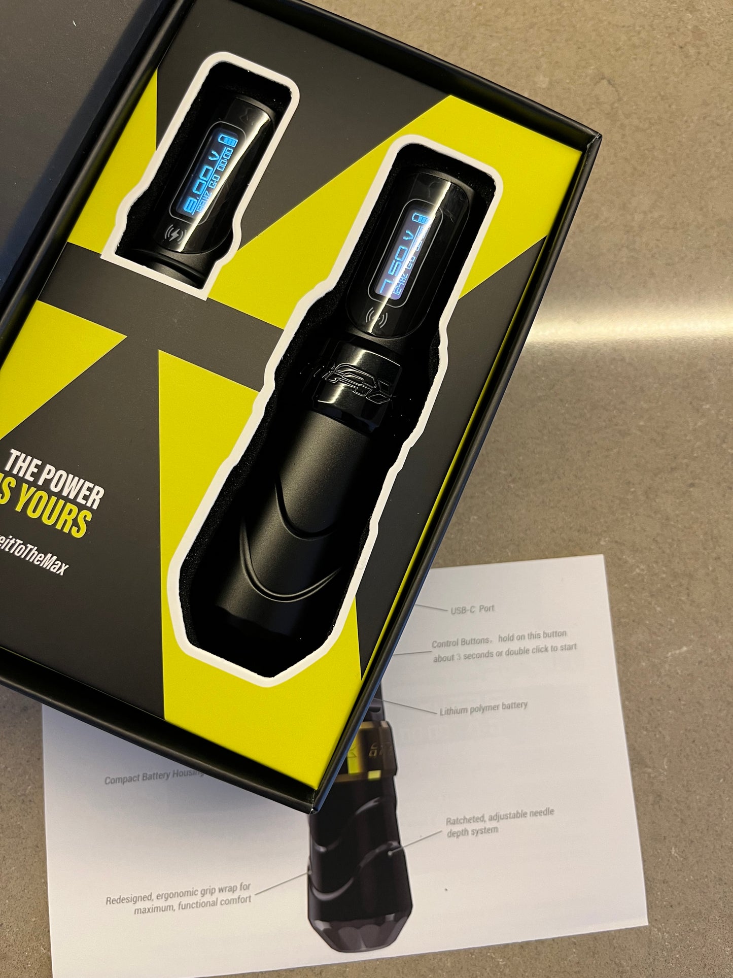 Photograph of a black 'Pen' type wireless machine details, featuring a 3.0 mm needle. The machine's box is opened, revealing its contents: two batteries. The cable attachment is not visible in the photo.