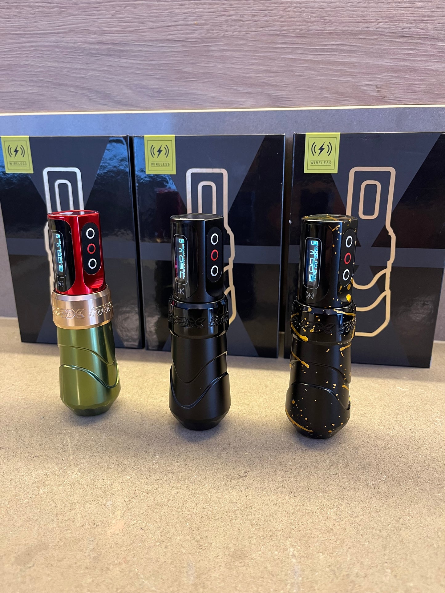 Photograph featuring three wireless 'Pen' type machines in different colors arranged side by side. Behind them are closed boxes of the same machines