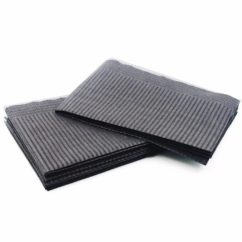 Stacked black disposable mats for professional use